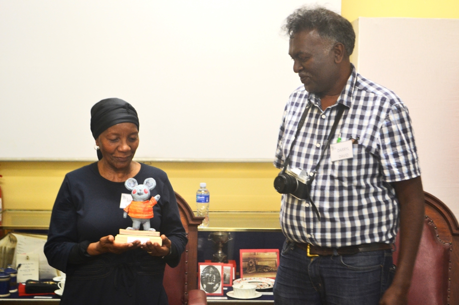 Sindiwe Magona receives the inaugural Children's Laureate Award from Darryl David, convener of the South African Festival of Children's Literature. The award was initially granted in an online ceremony in 2021, and the physical ceremony was held at the Simonstown ‘Books on the Bay’ literary festival in 2023.